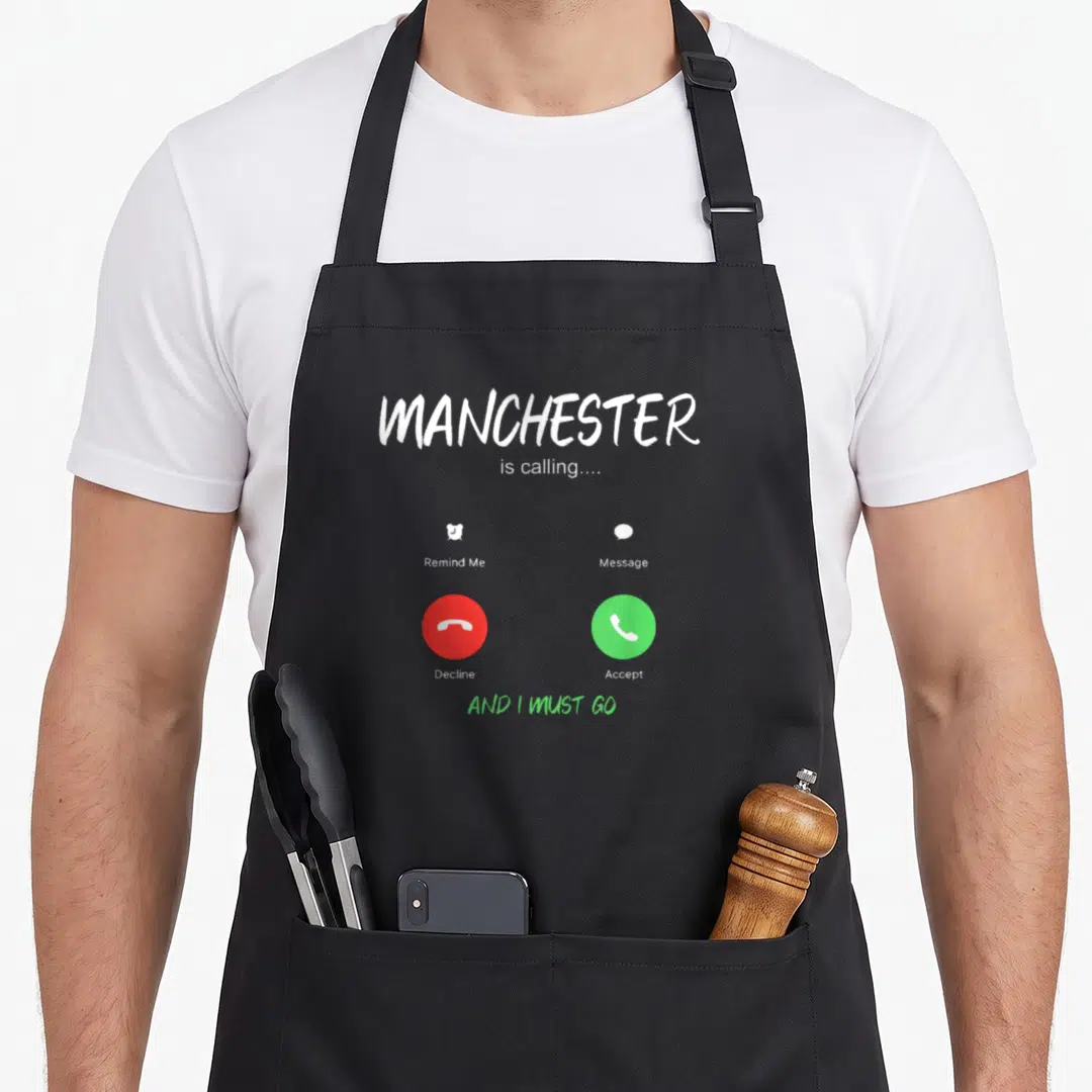 Manchester england apron - Smartphone call screen with MANCHESTER is calling text and red and green buttons — shown on a black cotton canvas apron against a white background