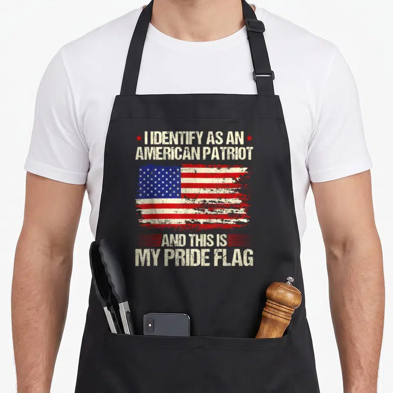 Pride american flag apron - Distressed US flag between text reading I IDENTIFY AS AN AMERICAN PATRIOT AND THIS IS MY — shown on a black cotton canvas apron against a white background