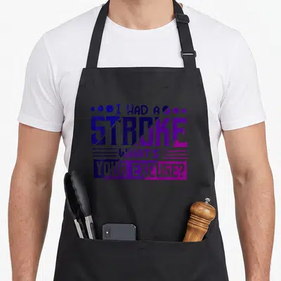 Funny excuse stroke awareness apron - Stacked text I HAD A STROKE WHAT'S YOUR EXCUSE? in blue purple magenta — shown on a black cotton canvas apron against a white background