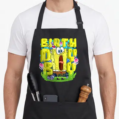 Squarepant birthday apron - SpongeBob with BIRTH DAY BOY text, pink jellyfish, and green seaweed — shown on a black cotton canvas apron against a white background