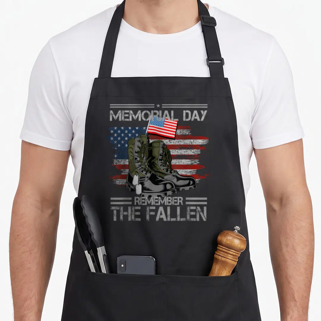 Memorial 4th of july apron - Olive combat boots with dog tags and distressed US flag, memorial day remember the fallen — shown on a black cotton canvas apron against a white background