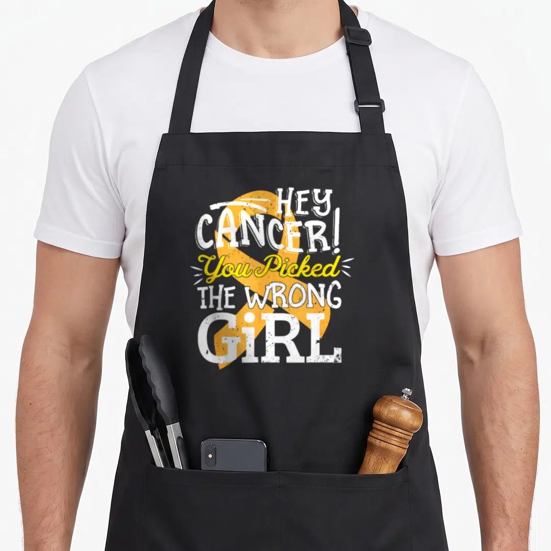 Childhood crab legs apron - Distressed white and yellow text reading HEY CANCER! You Picked THE WRONG GiRL over a large — shown on a black cotton canvas apron against a white background