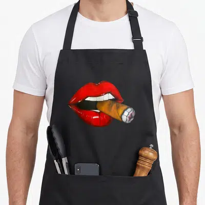 Cuban smoking apron - Realistic red lips holding a brown cigar with white teeth visible — shown on a black cotton canvas apron against a white background