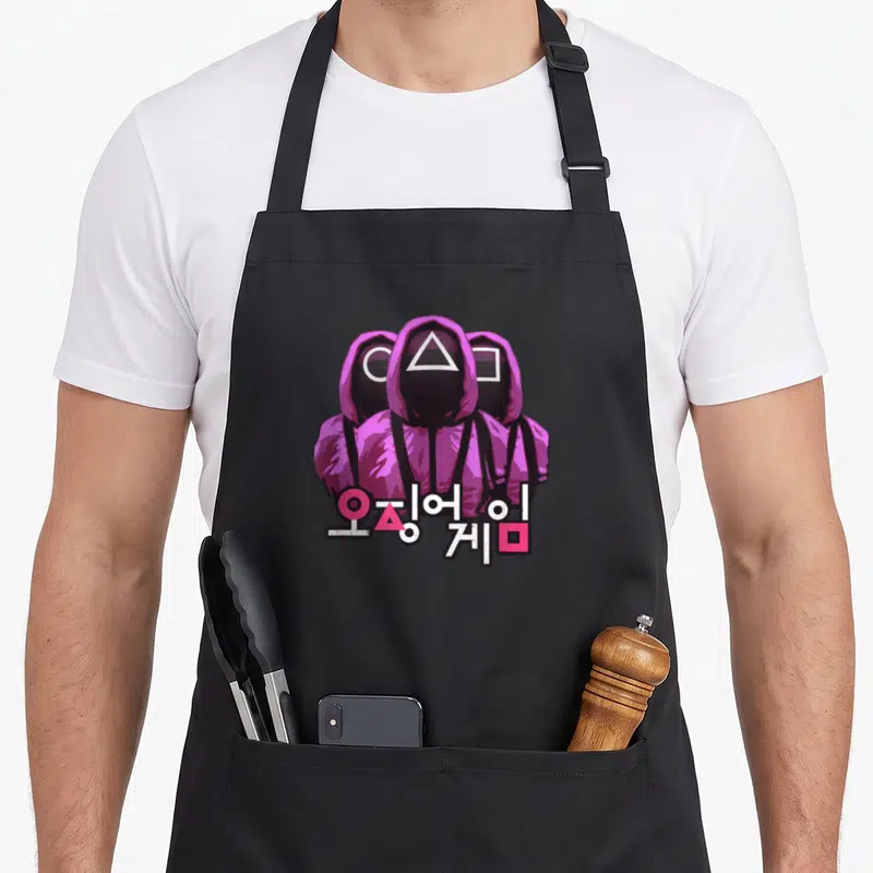 Three squid apron - Three pink hooded guards with triangle circle square masks and Korean text below — shown on a black cotton canvas apron against a white background