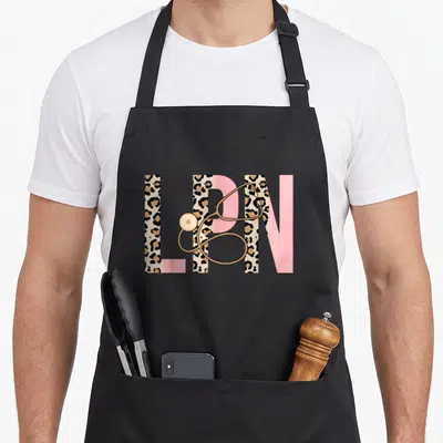 Lpn leopard nurse apron - Large LPN letters filled with leopard print and pink blocks with a gold stethoscope draped — shown on a black cotton canvas apron against a white background