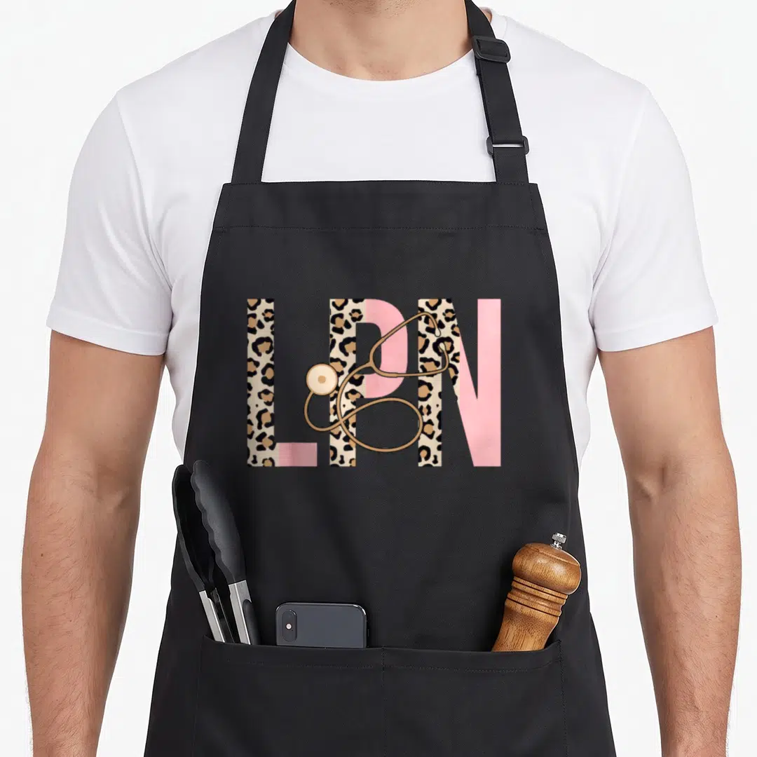 Lpn leopard nurse apron - Large LPN letters filled with leopard print and pink blocks with a gold stethoscope draped — shown on a black cotton canvas apron against a white background