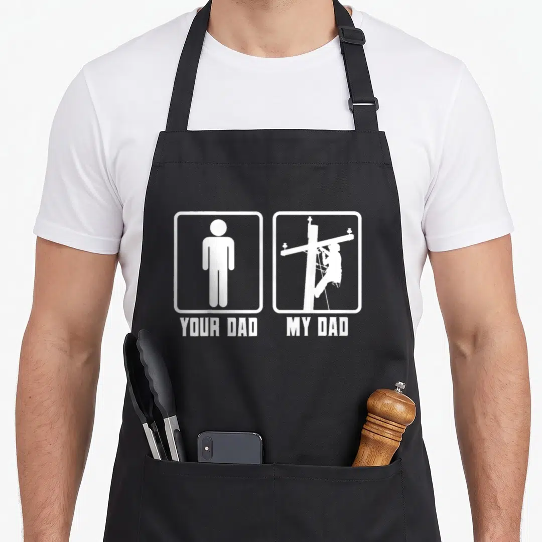 Electrical electricians apron - White minimalist graphic of a stick figure next to a lineman on a pole with text labels — shown on a black cotton canvas apron against a white background