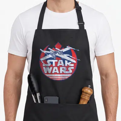 Symbol x apron - Distressed spaceship over red blue circle with white Star Wars text — shown on a black cotton canvas apron against a white background