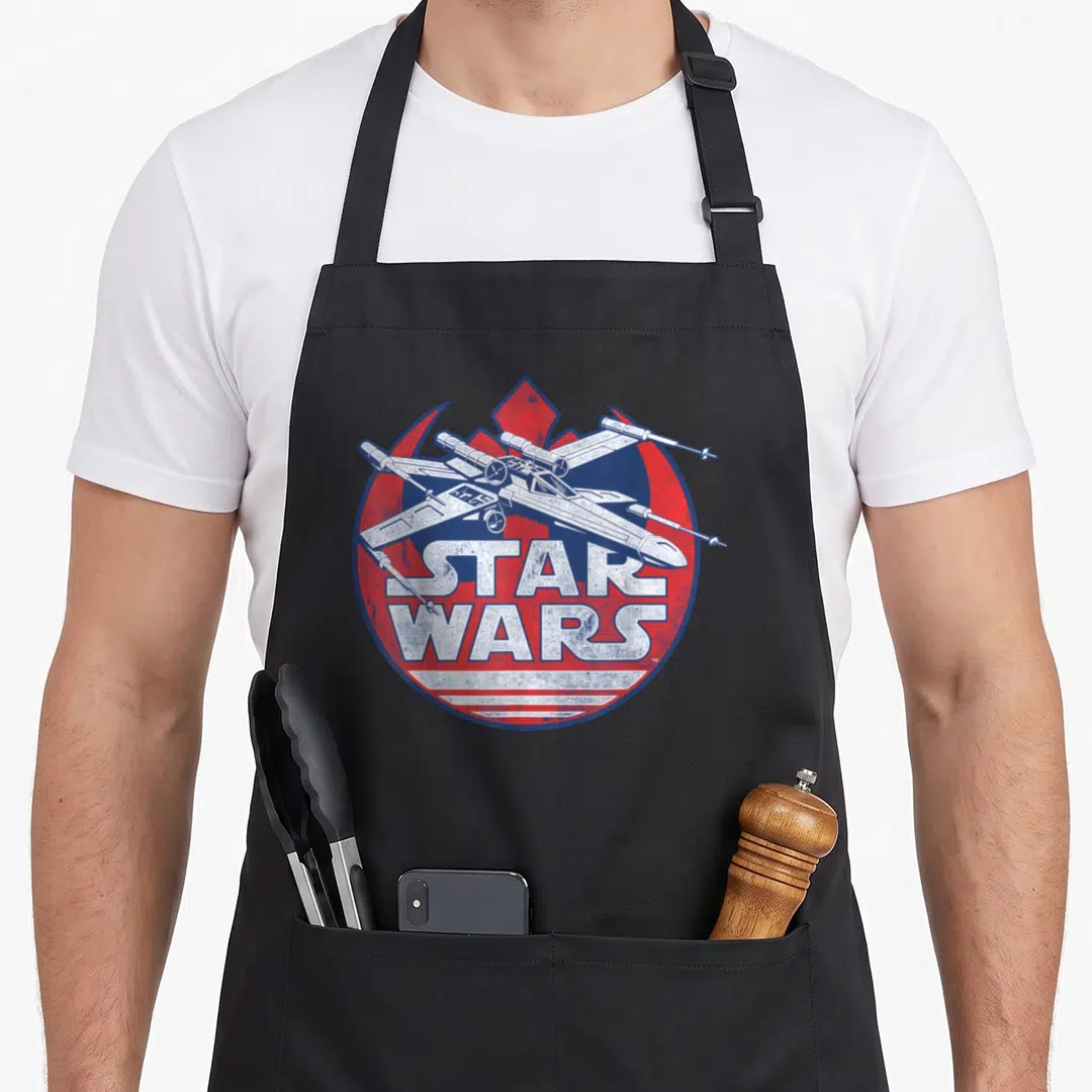 Symbol x apron - Distressed spaceship over red blue circle with white Star Wars text — shown on a black cotton canvas apron against a white background