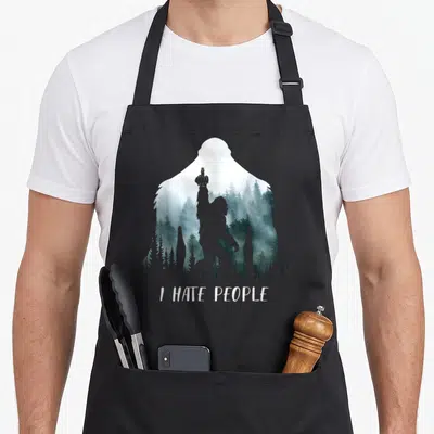 Hate bigfoot camping apron - Bigfoot silhouette filled with misty forest and I HATE PEOPLE text — shown on a black cotton canvas apron against a white background