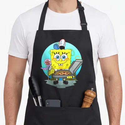 Krusty pizza apron - SpongeBob holding open pizza box beside pink The Krusty Krab sign — shown on a black cotton canvas apron against a white background