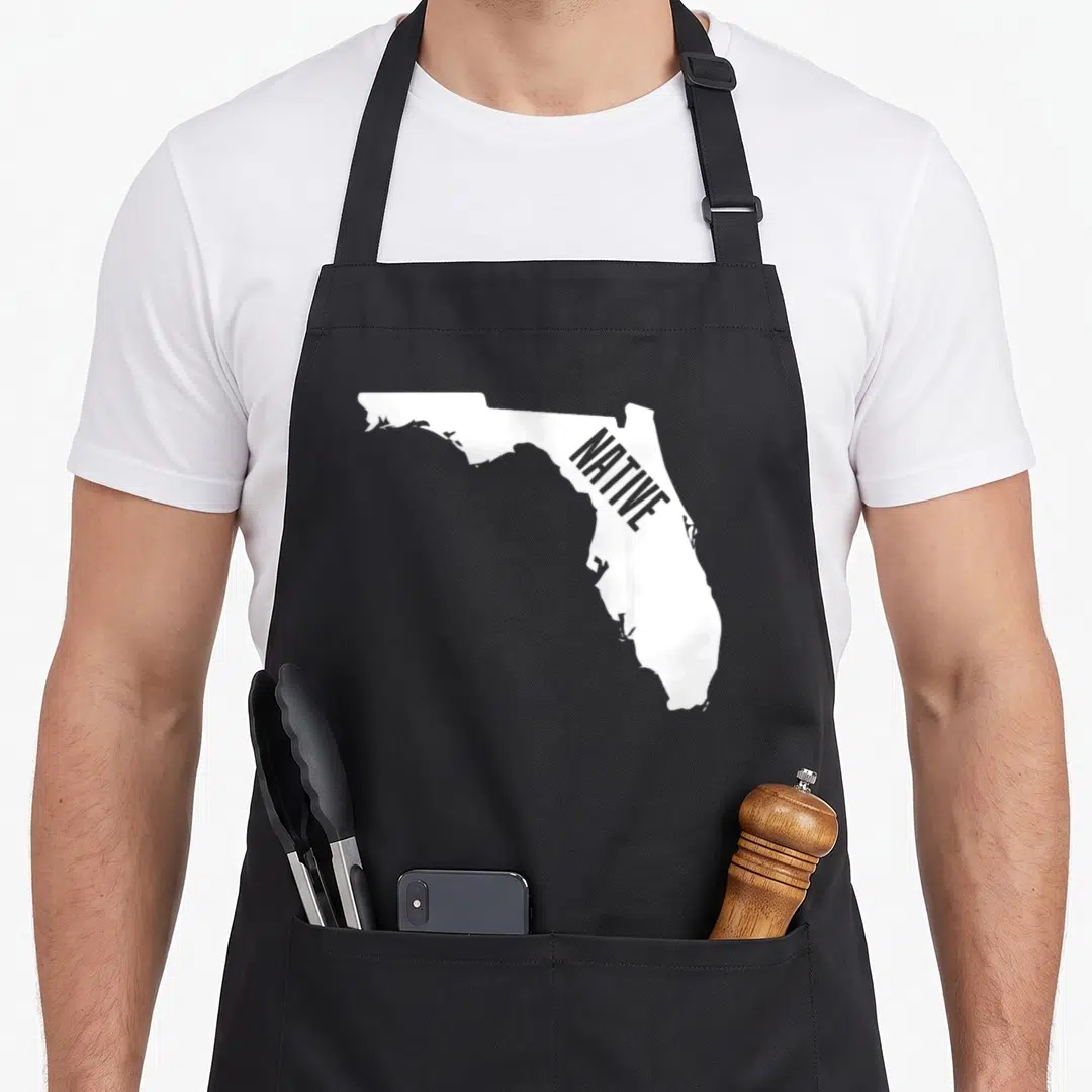 Native outline of an apron - White Florida map silhouette with grey diagonal NATIVE text on dark background — shown on a black cotton canvas apron against a white background