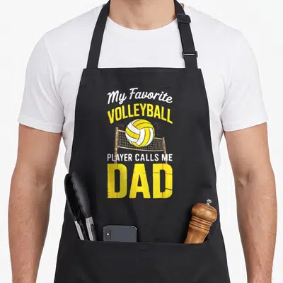 Volleyball player father day apron - My Favorite Volleyball Player Calls Me Dad text with yellow ball and brown net — shown on a black cotton canvas apron against a white background