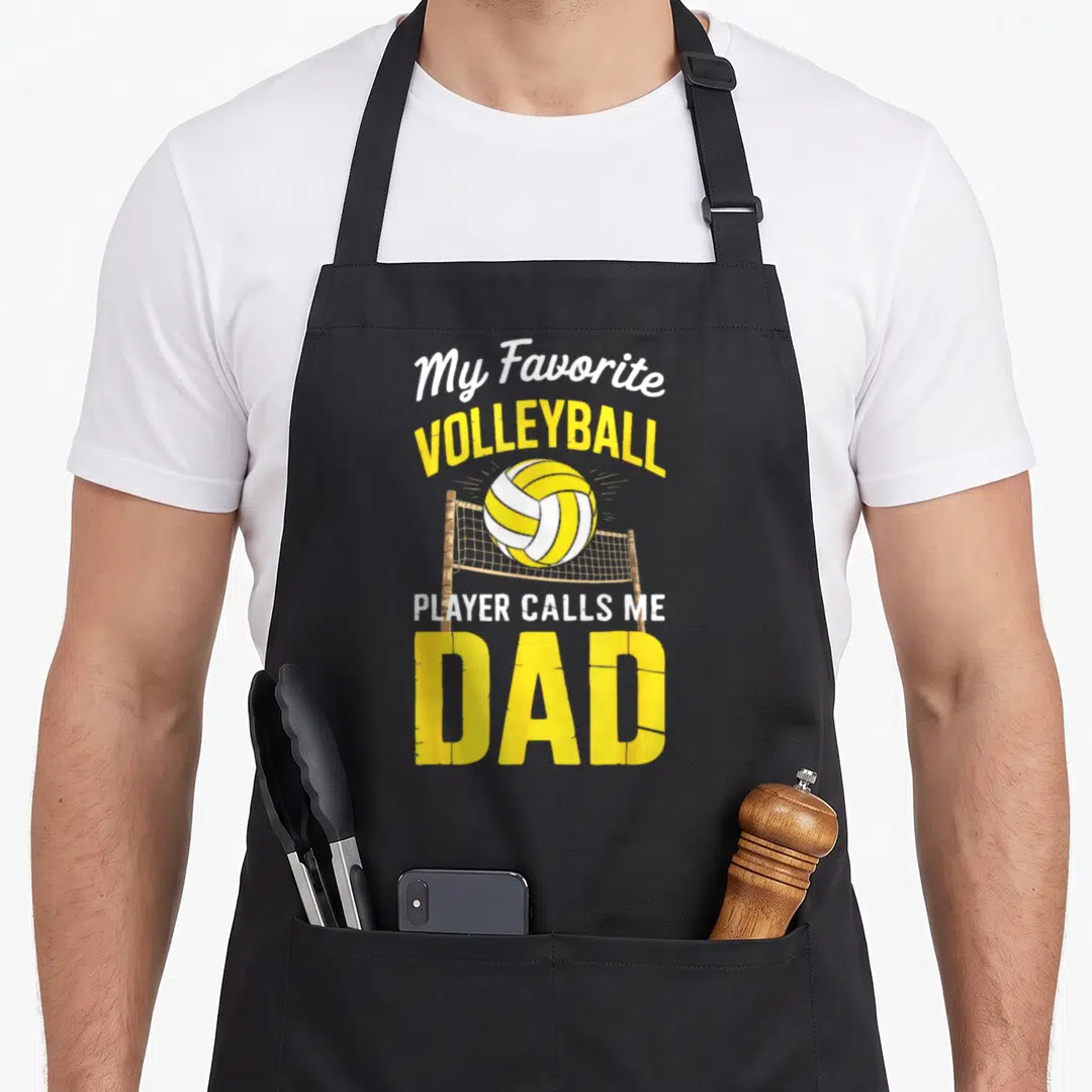 Volleyball player father day apron - My Favorite Volleyball Player Calls Me Dad text with yellow ball and brown net — shown on a black cotton canvas apron against a white background