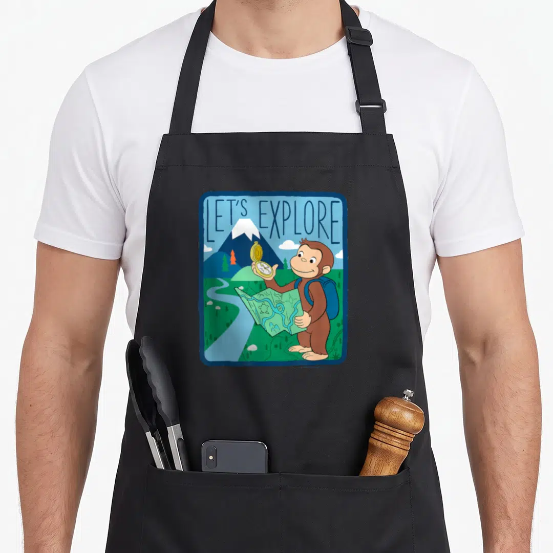 Curious outdoor apron - Cartoon monkey holding compass and map under LET'S EXPLORE text in blue-green-brown landscape — shown on a black cotton canvas apron against a white background