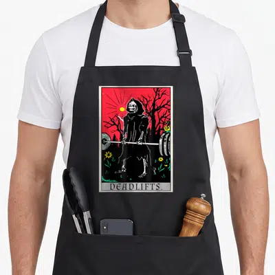 Tarot deadlift apron - Grim reaper lifting barbell under red sky with yellow sun and green flowers — shown on a black cotton canvas apron against a white background