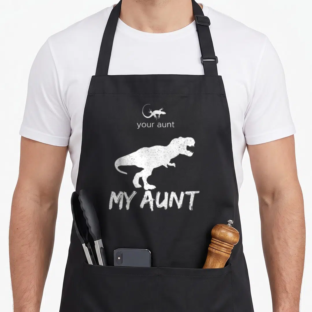 Lizard dinosaur apron - White distressed T-Rex and small lizard with your aunt my aunt text — shown on a black cotton canvas apron against a white background