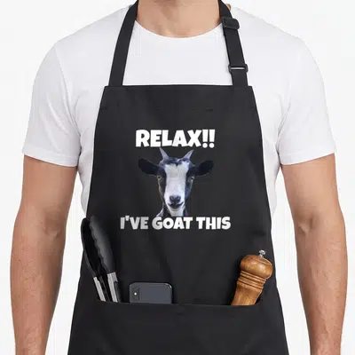 Relax goat apron - Goat photo with text RELAX!! I'VE GOAT THIS in white — shown on a black cotton canvas apron against a white background