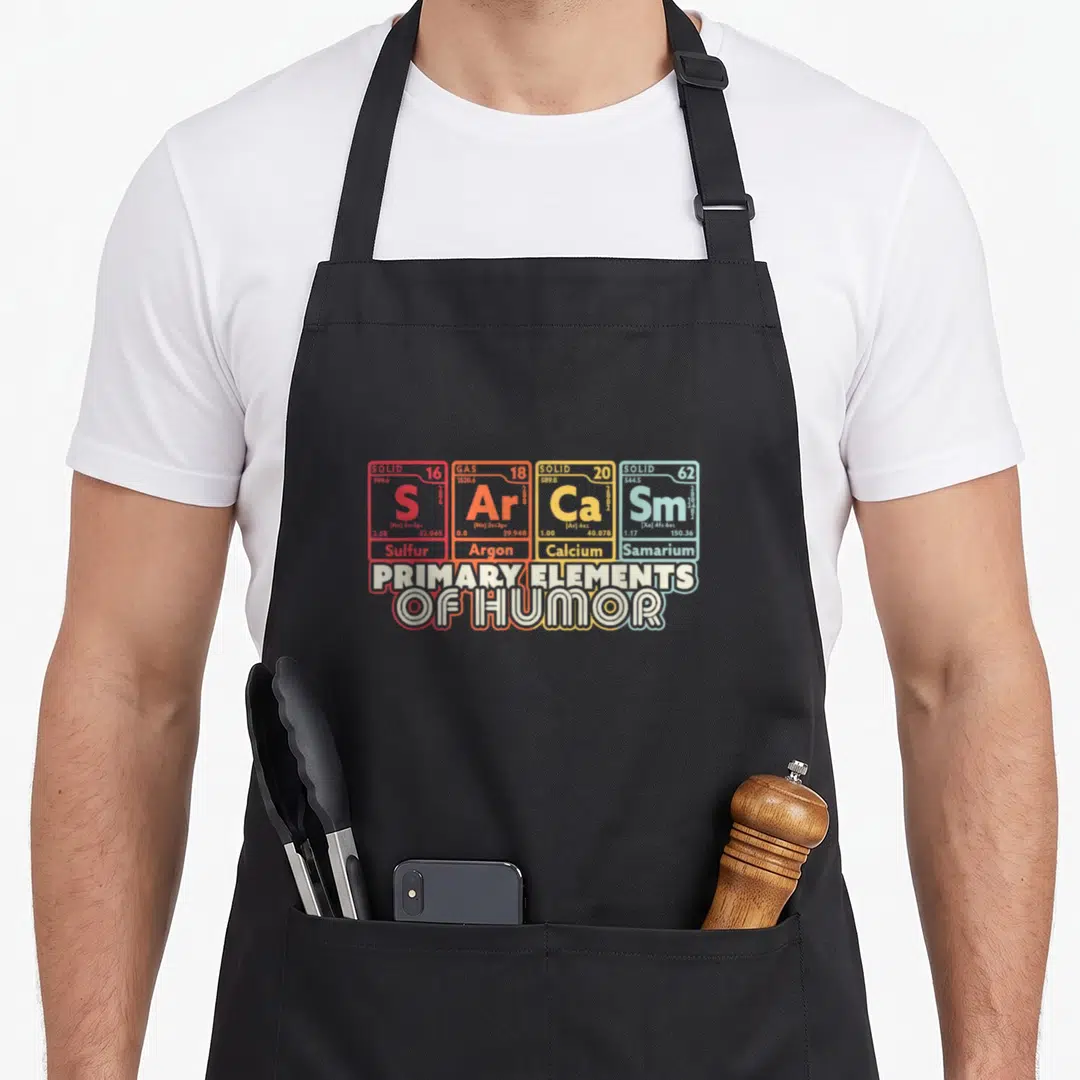Sarcasm science apron - Four colored periodic table tiles for Sulfur Argon Calcium Samarium above stacked text reading — shown on a black cotton canvas apron against a white background