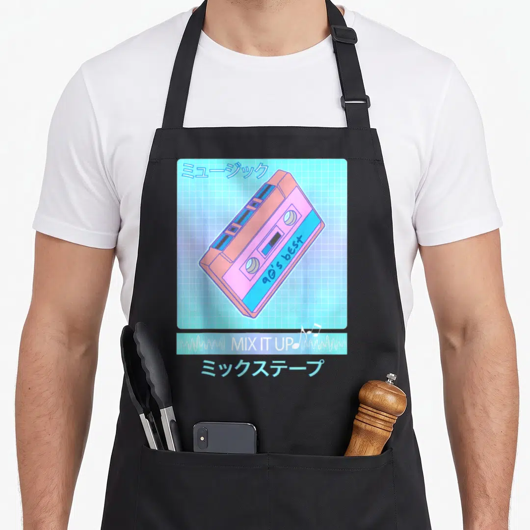 Mix 90s apron - Pink and blue cassette tape with Japanese text and MIX IT UP bar on grid background — shown on a black cotton canvas apron against a white background