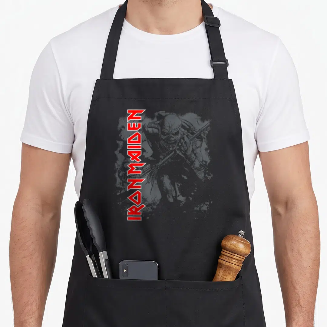 Contrast camping apron - Vertical red IRONMAIDEN text beside grey distressed zombie soldier illustration — shown on a black cotton canvas apron against a white background