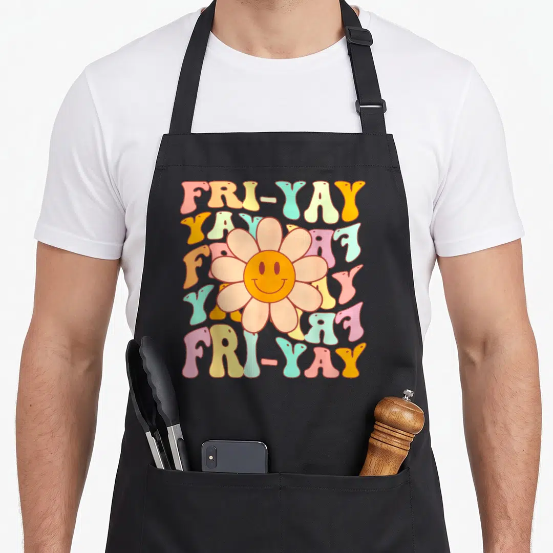 Flower teacher apron - Retro FRI-YAY text rows behind a centered smiley flower in pastel colors — shown on a black cotton canvas apron against a white background