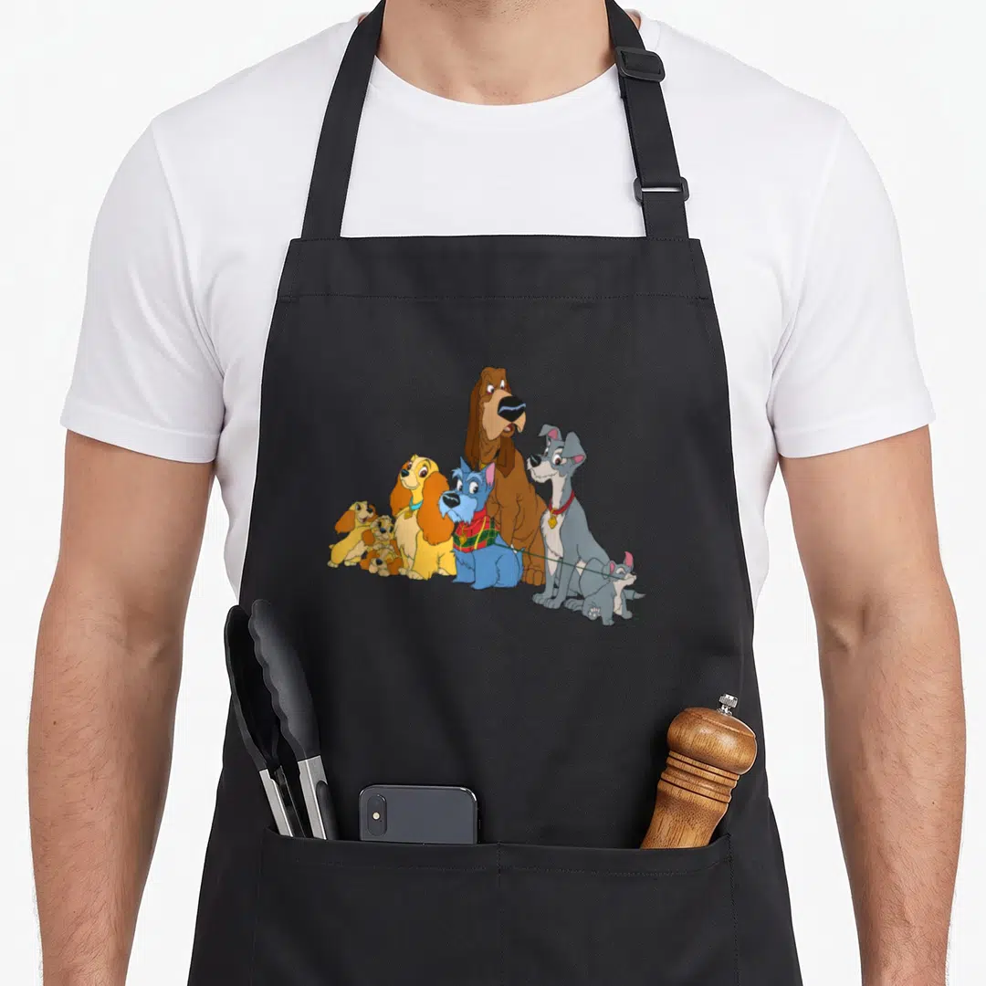 Dog lady and the tramp apron - Six cartoon dogs facing right in brown blue grey and yellow — shown on a black cotton canvas apron against a white background