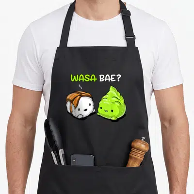 Wasa sushi apron - Cartoon salmon sushi and green wasabi with text WASA BAE? in speech bubble — shown on a black cotton canvas apron against a white background