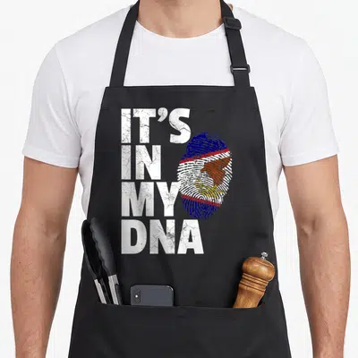 Dna american flag apron - IT'S IN MY DNA text next to a fingerprint containing the American Samoa flag and eagle — shown on a black cotton canvas apron against a white background