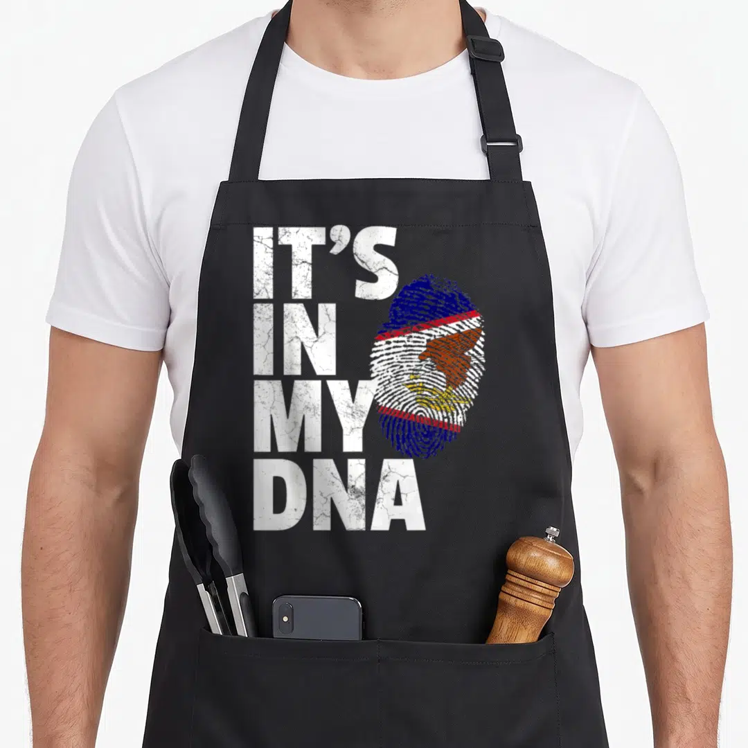Dna american flag apron - IT'S IN MY DNA text next to a fingerprint containing the American Samoa flag and eagle — shown on a black cotton canvas apron against a white background