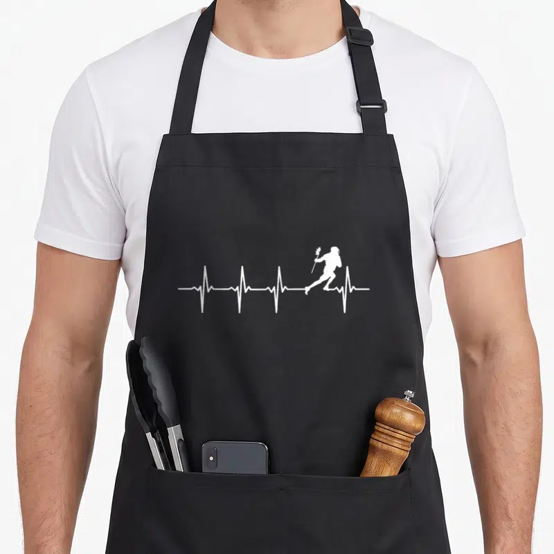 Heartbeat lacrosse player apron - White heartbeat line with lacrosse player silhouette running across the center — shown on a black cotton canvas apron against a white background
