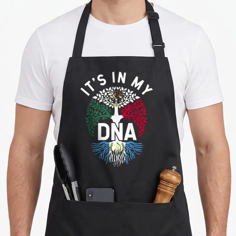 Mixed mexican apron - Tree with green red white blue sections and IT'S IN MY DNA text — shown on a black cotton canvas apron against a white background