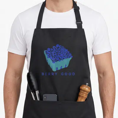 Berry blueberries apron - BERRY GOOD text below a dark blue and light blue blueberry cluster in a teal liner — shown on a black cotton canvas apron against a white background
