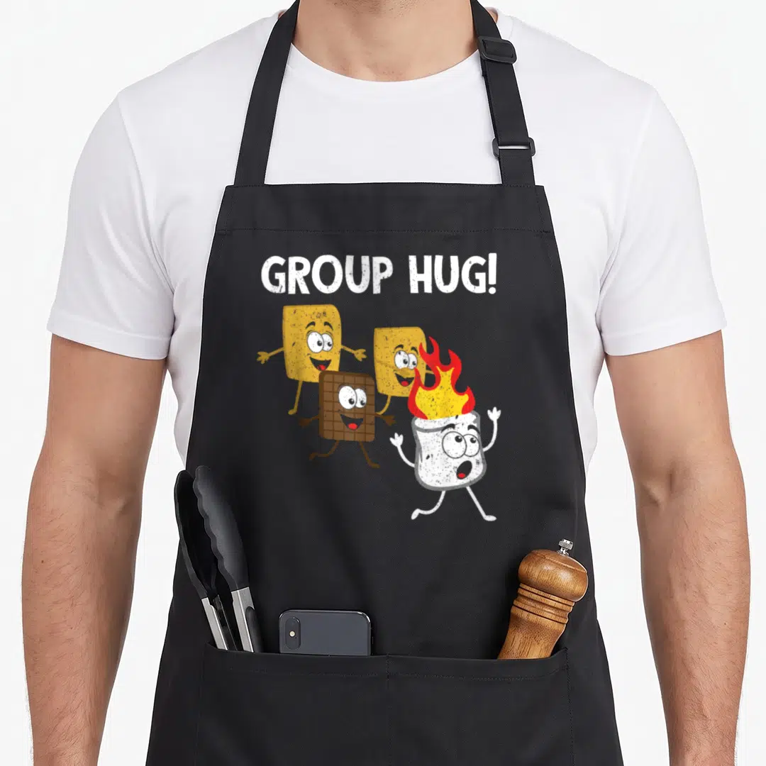 Smore food aprons - Cartoon marshmallow on fire running with crackers and chocolate under GROUP HUG text — shown on a black cotton canvas apron against a white background