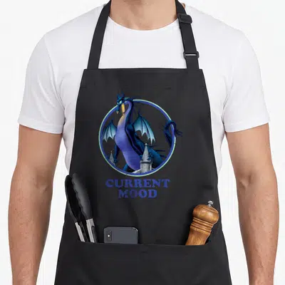 Current beauty apron - Blue and purple dragon inside a circle with grey castle towers and text CURRENT MOOD — shown on a black cotton canvas apron against a white background