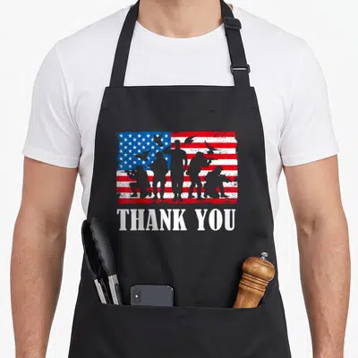 Thank military apron - Soldier silhouettes and doves on distressed flag with THANK YOU text — shown on a black cotton canvas apron against a white background
