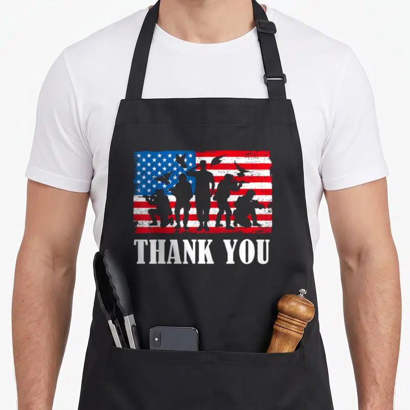 Thank military apron - Soldier silhouettes and doves on distressed flag with THANK YOU text — shown on a black cotton canvas apron against a white background