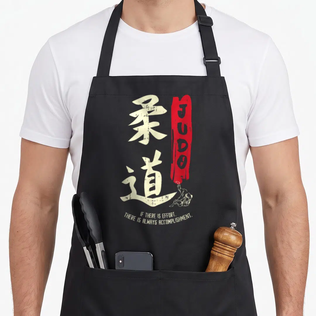 Japanese judo apron - White Kanji characters next to a red vertical JUDO brush stroke with two small line-art figures — shown on a black cotton canvas apron against a white background