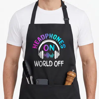 Music headphones apron - Gradient text HEADPHONES ON WORLD OFF over white headphones with sound wave — shown on a black cotton canvas apron against a white background