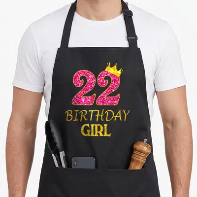 22nd princess apron - Pink glitter number 22 with gold crown and stacked birthday girl text — shown on a black cotton canvas apron against a white background
