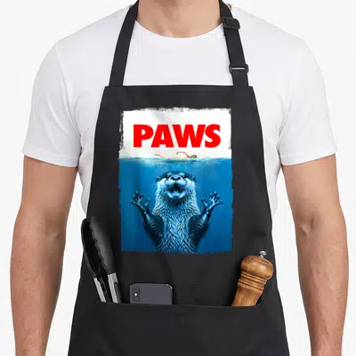 Paw otter mom apron - PAWS text above swimmer and underwater otter in blue and red — shown on a black cotton canvas apron against a white background