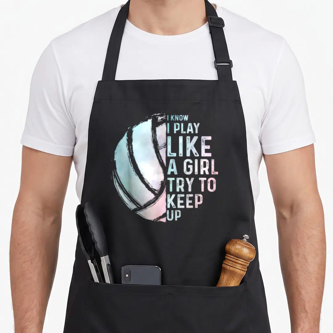 Youth girls volleyball apron - Watercolor volleyball and I Know I Play Like A Girl text in blue pink white — shown on a black cotton canvas apron against a white background