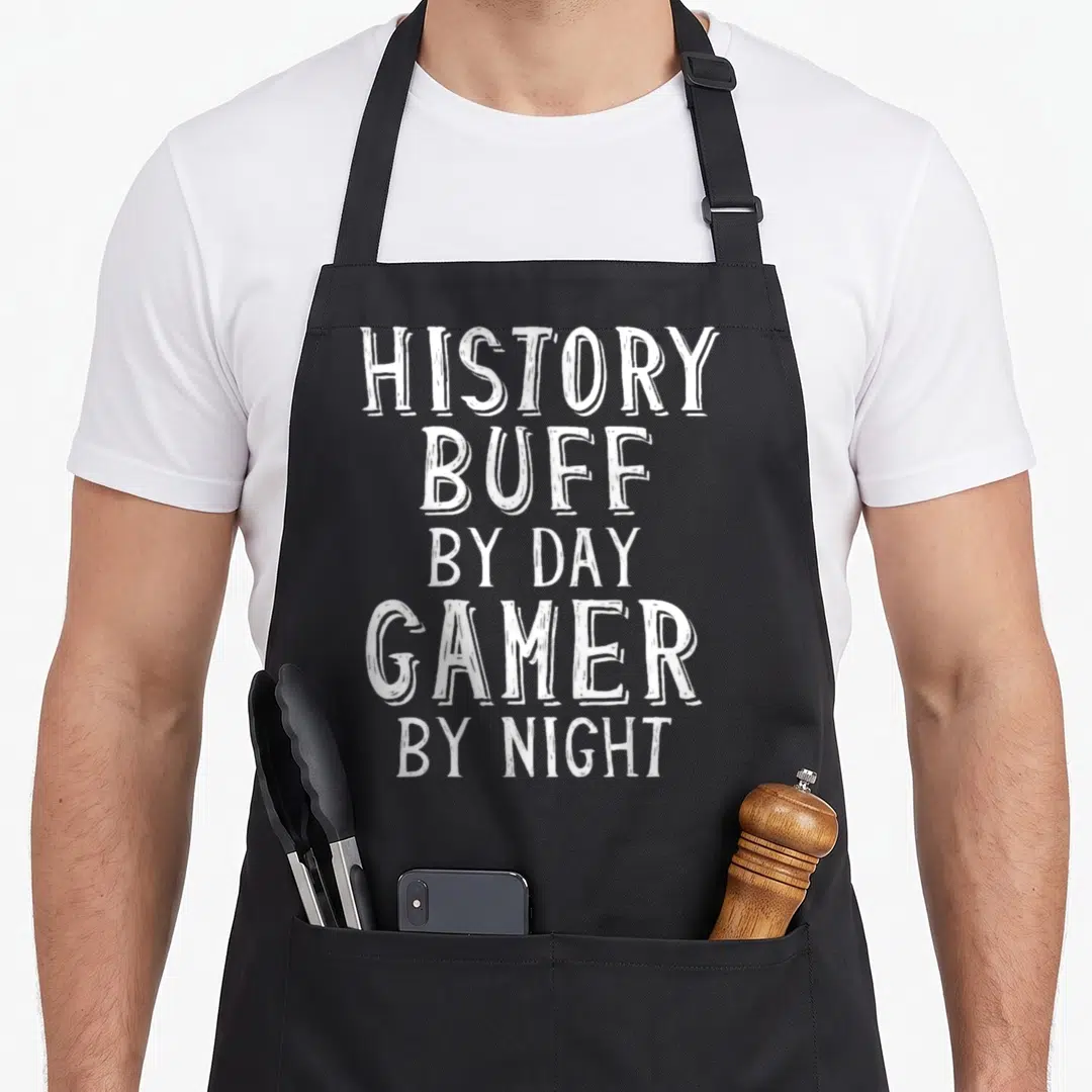 History gaming apron - White stacked typography reading History Buff By Day Gamer By Night on grey background — shown on a black cotton canvas apron against a white background