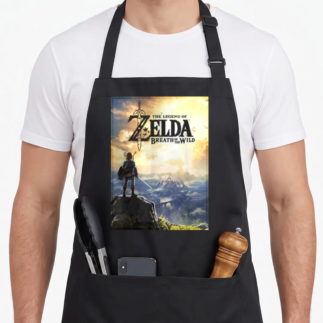 Horizon legend apron - Link standing on rock facing castle with title text over sword in blue gold grey yellow — shown on a black cotton canvas apron against a white background