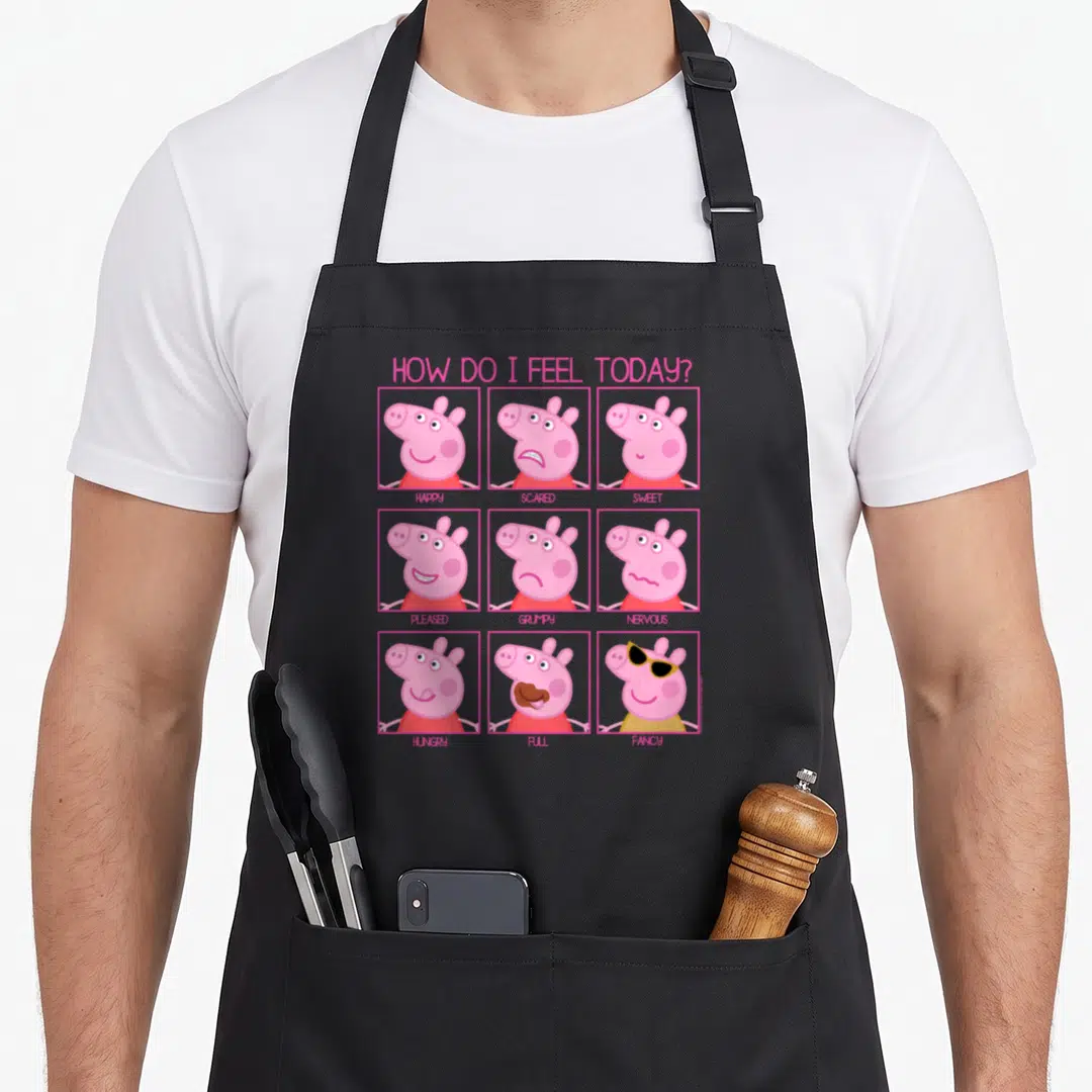 Feel pig apron - Peppa Pig nine-face emotion grid with pink borders and descriptive words — shown on a black cotton canvas apron against a white background