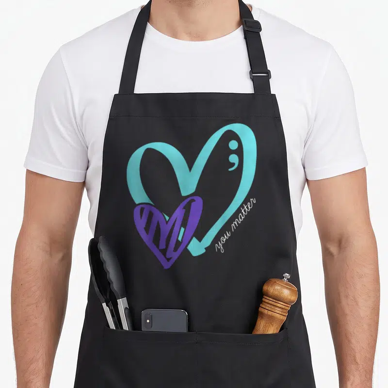 Matter depression awareness apron - Light blue heart with semicolon, overlapping purple heart, white you matter script — shown on a black cotton canvas apron against a white background