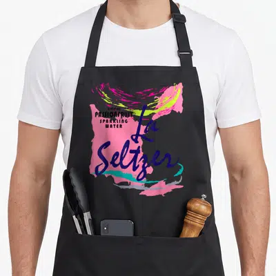 Passionfruit halloween apron - La Seltzer script text over pink and turquoise paint splashes with stacked flavor details — shown on a black cotton canvas apron against a white background