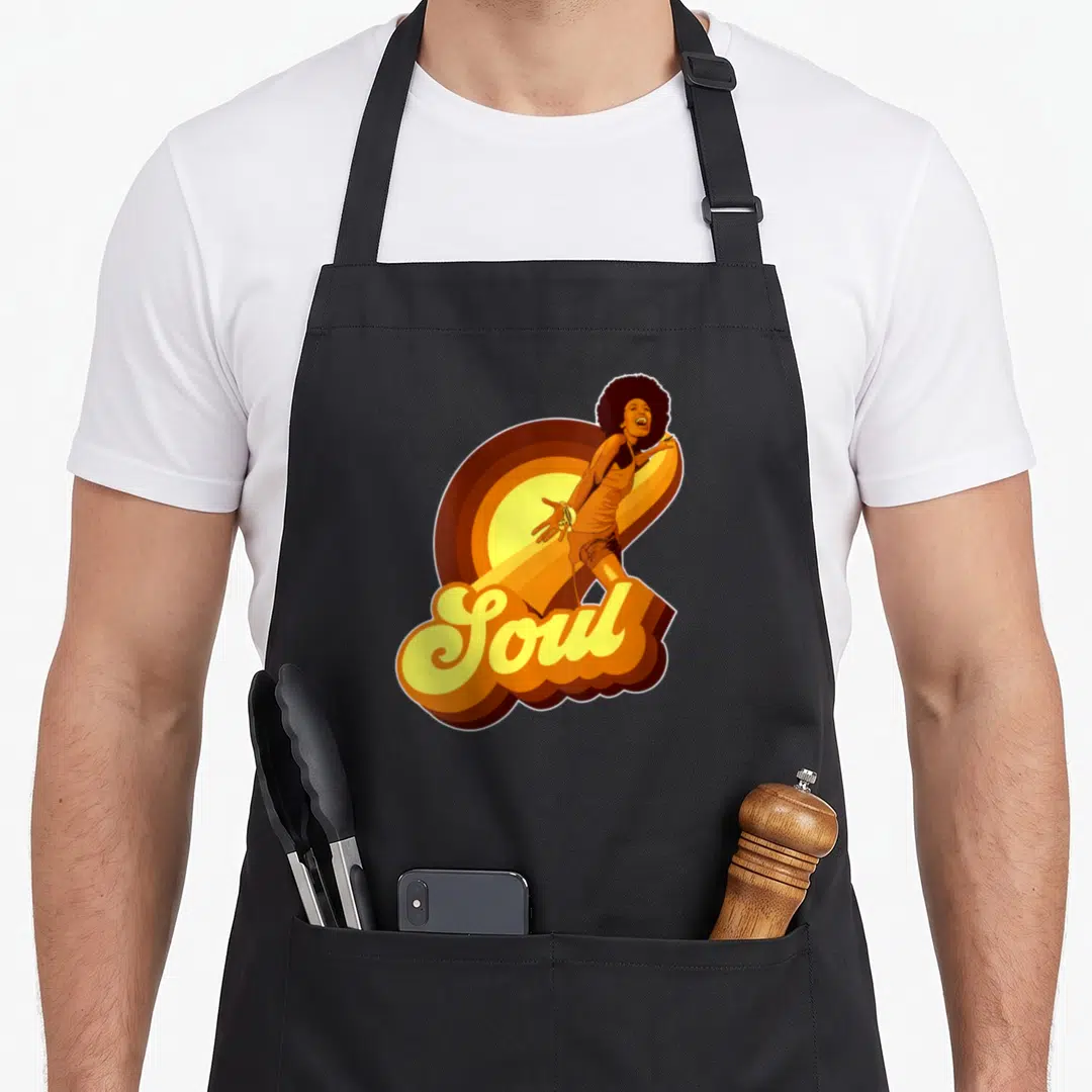 Funny funk 70s apron - Woman with afro and Soul script in yellow orange brown sunburst — shown on a black cotton canvas apron against a white background