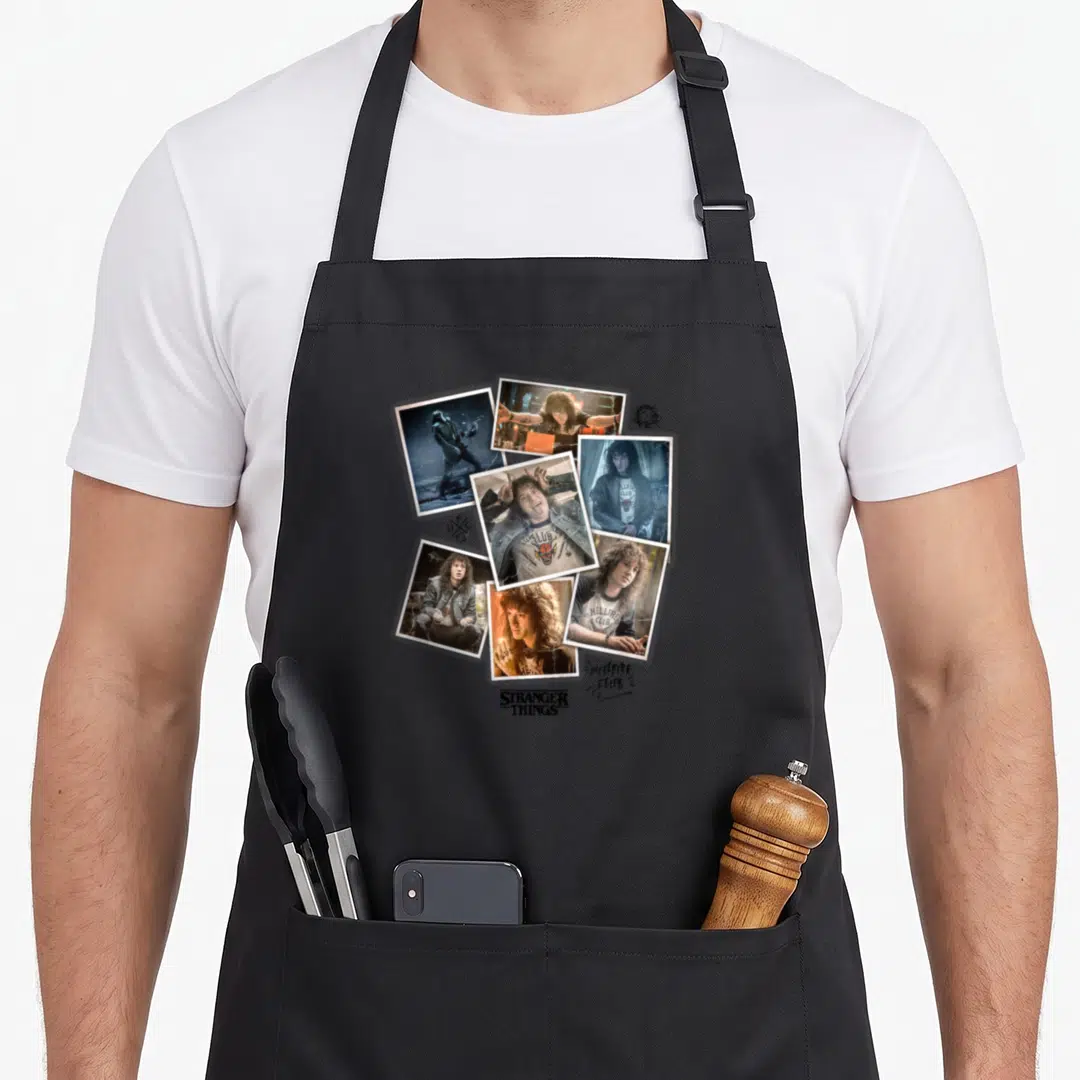 Eddie fan club apron - Six polaroid photos of Eddie Munson with Hellfire Club text and Stranger Things logo — shown on a black cotton canvas apron against a white background