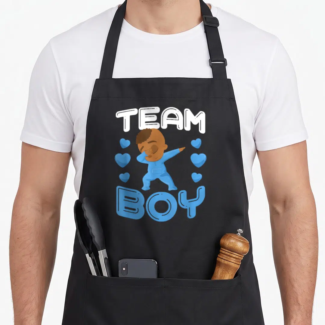 Gender uab kidkis apron - Cartoon baby dabbing with Team Boy text and blue hearts — shown on a black cotton canvas apron against a white background